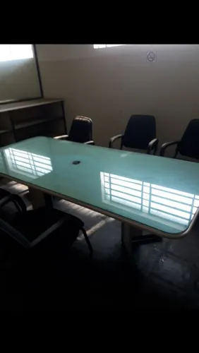Mesa de reunião de diretoria com uma poltrona giratória e seis cadeiras fixas com braços 