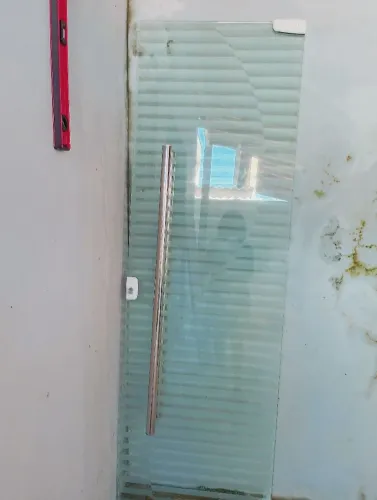 Porta de vidro temperado com detalhe jateado com puxador de metal tubular 
