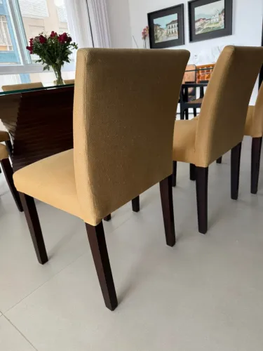 Conjunto com 8 cadeiras de madeira escura, estofadas com tecido de linho na cor mostarda.
