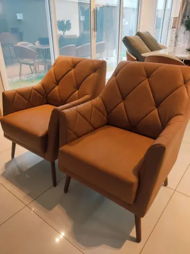Poltronas em facto marrom pés palito em madeira.