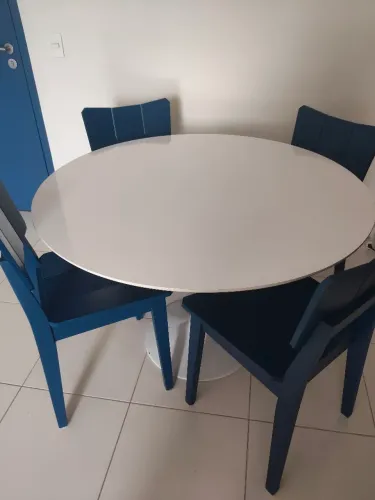 Conjunto de mesa redonda com tampo de laca branca e 4 cadeiras azuis.