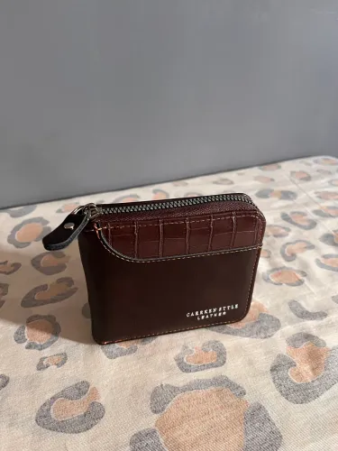 Carteira em couro com zíper e costura reforçada.