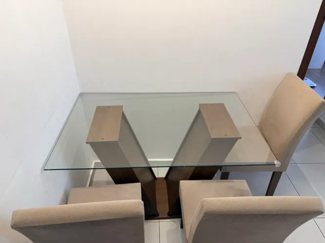 Mesa de jantar amadeirada com 4 cadeiras bege. Tampo de vidro