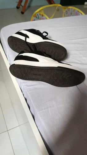 Tênis casual Puma Caven 2.0 preto com detalhes em dourado.