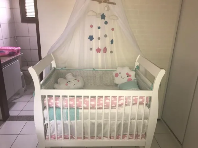 Berço de bebê branco com detalhes em rosa e verde