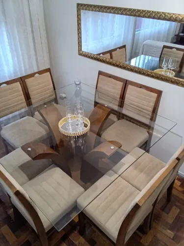 Mesa de jantar 8 lugares com tampo de vidro, base e cadeiras de madeira maciça.