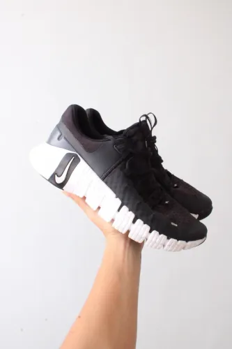 Nike Free Metcon 5 na cor preta com solado branco e detalhe do logo destacado.
