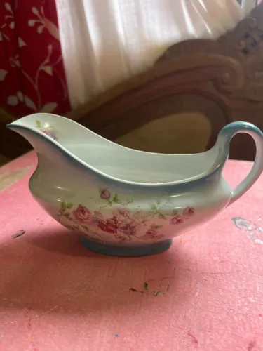 molheira antiga de porcelana com estampa de rosas e acabamento azulado na borda e na alça