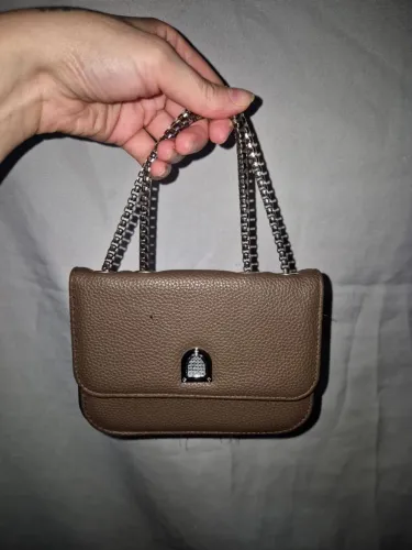 Mini bolsa marrom texturizada com alça de corrente prateada ajustável.