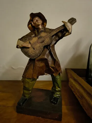 Escultura de homem com violão em papel machê