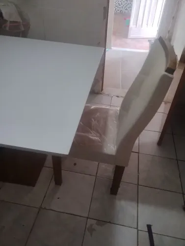 Mesa com quatro cadeiras de madeira com vidro por cima e algumas avarias 