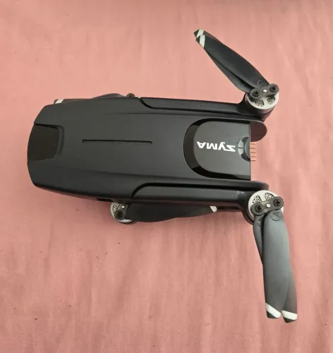 Drone Syma W3 dobrável, caracterizado pelo seu design compacto e cor preta.