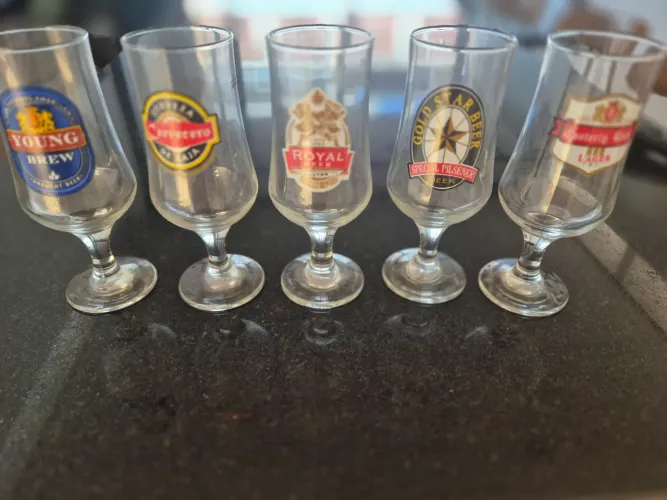 5 copos de cerveja com brasoes de cervejaria
