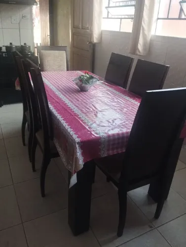 Mesa com 6 cadeiras de madeira com tampa de vidro no meio.