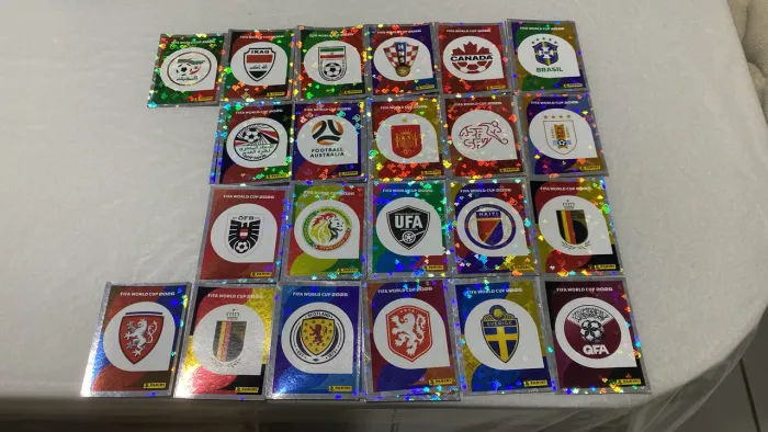 Figurinhas da copa 2026 brilhantes escudos das seleções.