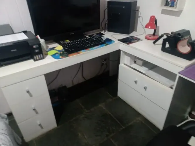 Mesa em L, branca, com 3 gavetas e armário. Marcas de uso. Estudo oferta.