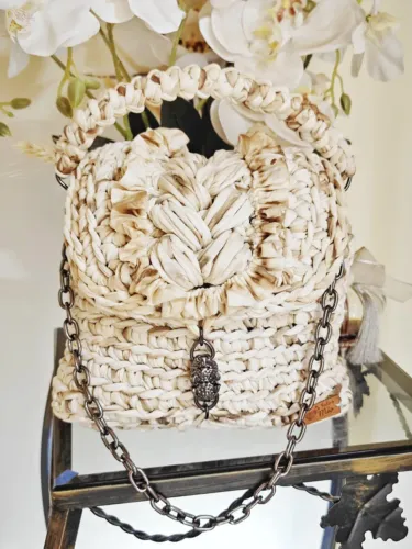 Bolsa de crochê com alças de mão de crochê e de corrente a tiracolo.