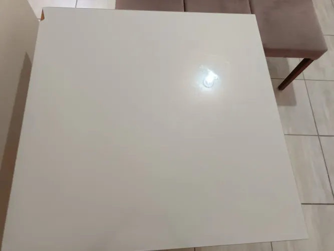 Mesa de vidro com 3 cadeiras tem um pedaço quebrado no canto .