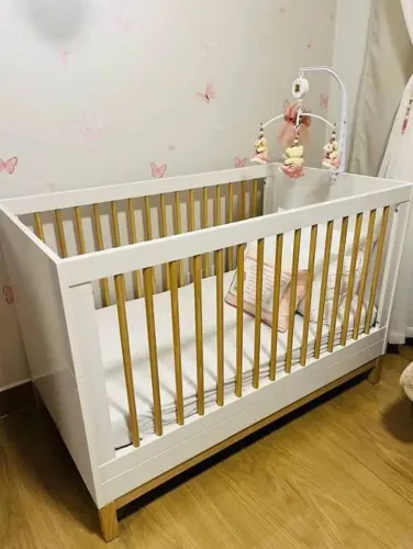 Berço de madeira com detalhes em branco vira cama e vai colchão 