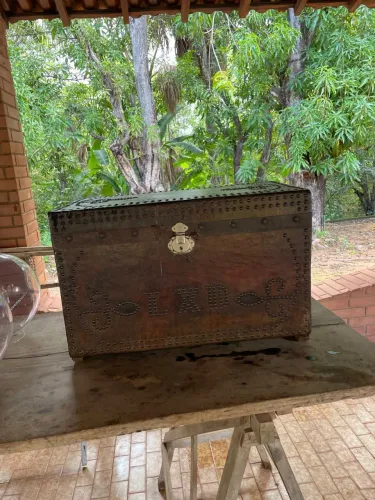 Baú antigo, em madeira e couro, iniciais LXD, detalhes metálicos. Preço: R$ 320,00