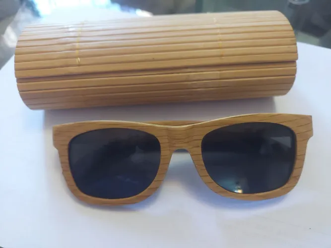 Óculos de sol armação artesanal em madeira com lentes escuras.