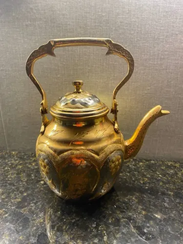 chaleira com cena floral em metal dourada em estilo arabe.