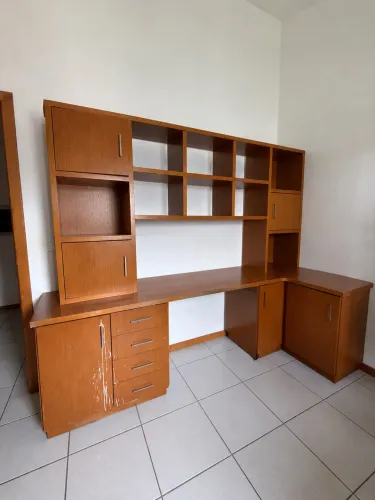 Escrivaninha em L com estante e armários.