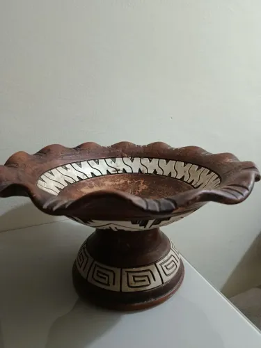 Fruteira  de cerâmica marron. Bordas onduladas e base pedestal. Pintura branca  ao redor