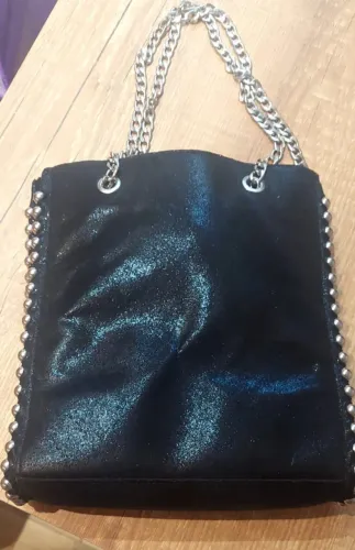 Bolsa preta brilhosa com alça de corrente e tachinas nas laterais