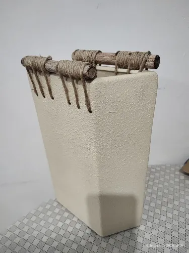 Vaso de cerâmica cor bege com madeira e cordas nas bordas