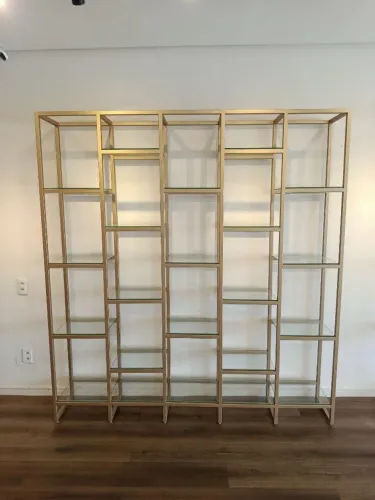Estante elegante, com estrutura metálica e prateleiras de vidro.