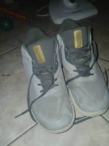 tênis de basquete Under Armour Bankshot em cinza com detalhes em dourado.