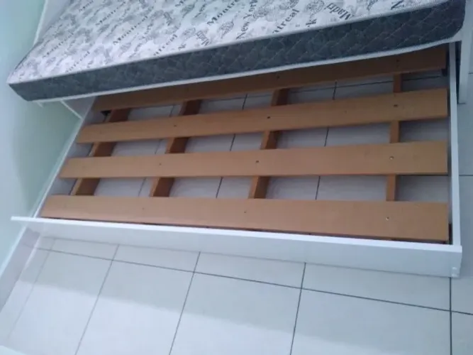 Cama auxiliar branca de MDF com colchão.