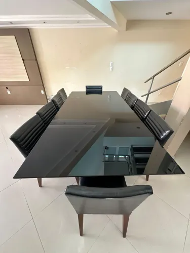 Mesa retangular em madeira com tampo de vidro preto mais 10 cadeiras em couro.