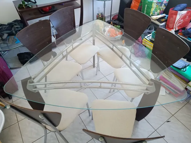 Mesa triangular de vidro com pé de madeira com seis cadeiras.