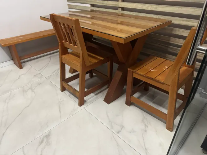 Mesa de madeira com tampa de vidro e cadeiras