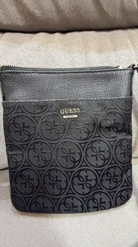 Bolsa Guess transversal preta, com estampa monograma da marca.