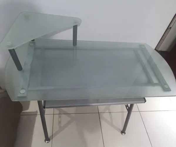 Uma mesa de computador usada de mesa de vidro jantiado e pé de ferro
