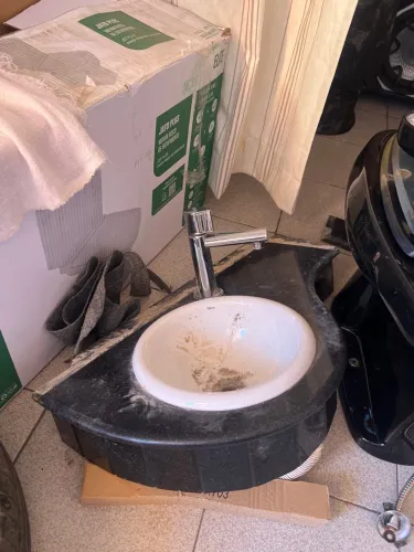 Armário com pia, vaso sanitário, e uma porta de box de vidro 