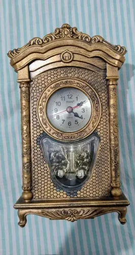 Relógio de mesa decorativo na cor dourada, em ótimo estado, possui detalhes em relevo