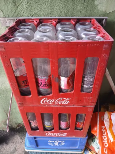 Duas caixas de Coca Cola retornável e uma de cerveja  chopinho