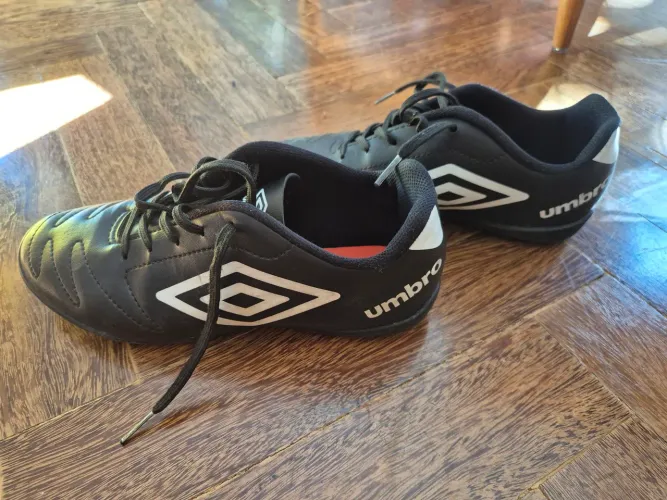 Chuteiras Umbro Society pretas com solado de micro travas para grama sintética.