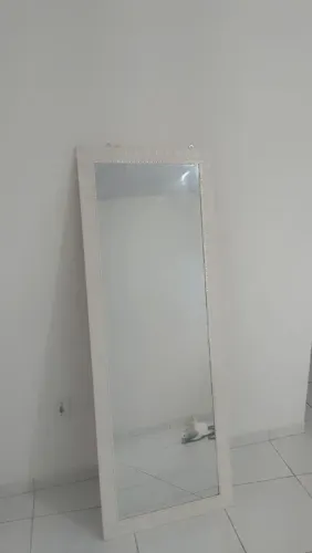 Espelho de corpo inteiro com moldura branca decorativa.