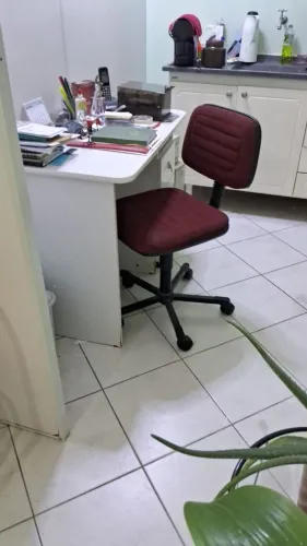 Mesa de estudo com gaveta, pontinha e cadeira de tecido vermelha.