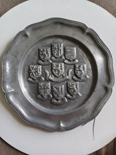 prato decorativo é feito de estanho e apresenta brasões das províncias belgas.