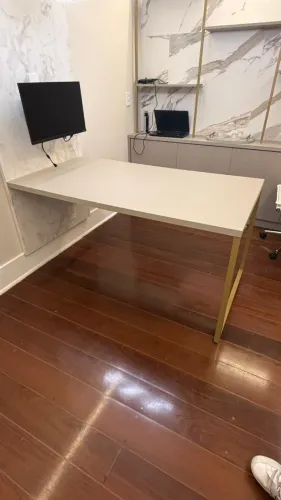 Mesa de MDF na cor Fendi com pé metálico dourado para fixação em parede.