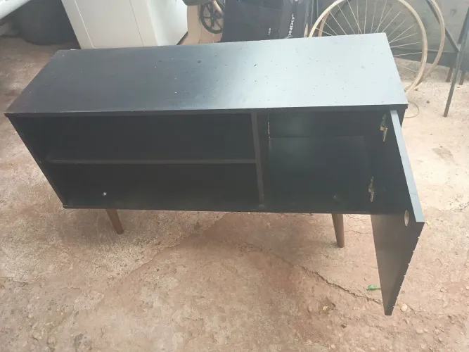 Um raque de sala preto com uma portinha duas prateleiras