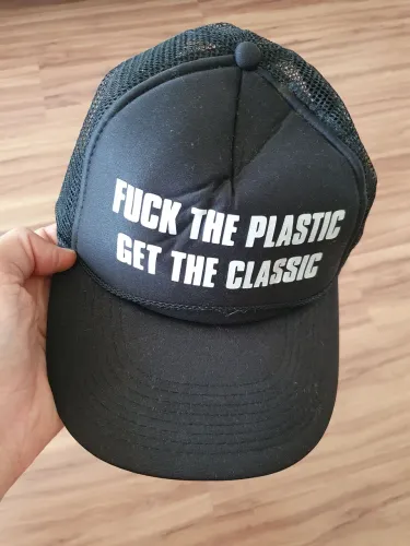 Boné trucker preto, usado, com tela traseira e frase ?FUCK THE PLASTIC / GET THE CLASSIC?.