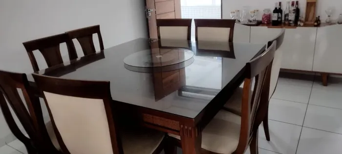 Mesa com tampo de vidro em madeira com 8 cadeiras acochoadas