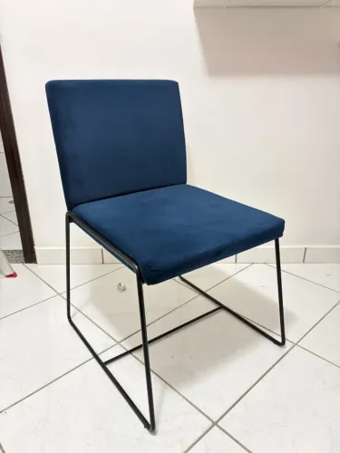 Cadeira de veludo azul com encosto em madeira e base metálica preta